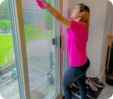 Cleaner cleaning patio windows during a residential house cleaning service.