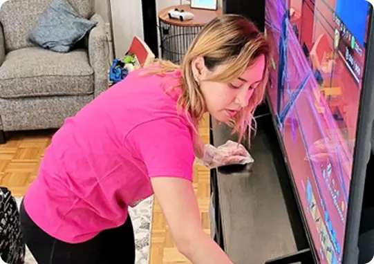 cleaner cleaning a tv stand during a house cleaning service.