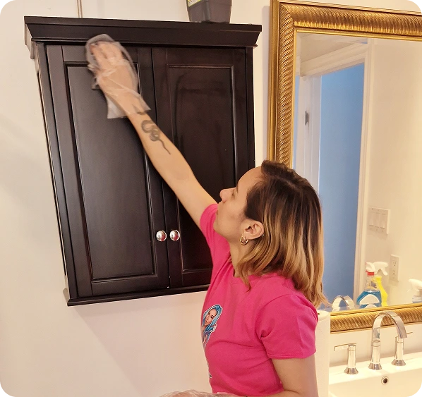 House cleaner cleaning a bathroom cabinet during a residential house cleaning service.